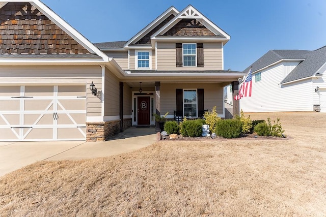 craftsman-style house with driveway, stone siding, and covered porch