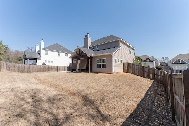 back of property featuring a fenced backyard, a chimney, a residential view, and a shingled roof