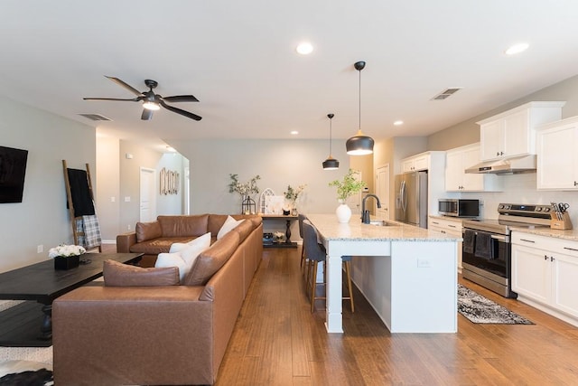 kitchen with appliances with stainless steel finishes, open floor plan, visible vents, and under cabinet range hood