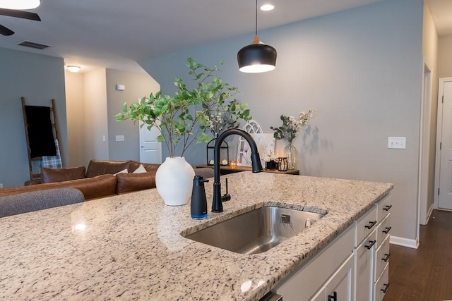 kitchen featuring visible vents, light stone counters, dark wood-type flooring, white cabinetry, and a sink