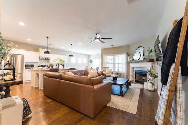 living room featuring a ceiling fan, recessed lighting, dark wood finished floors, and a tile fireplace