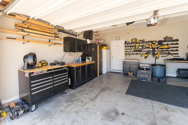 garage with a garage door opener, freestanding refrigerator, and a workshop area