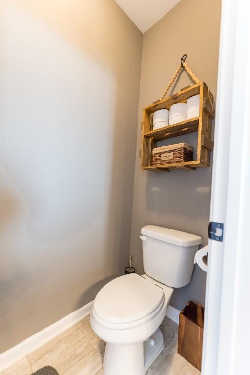 bathroom with toilet, baseboards, and tile patterned floors