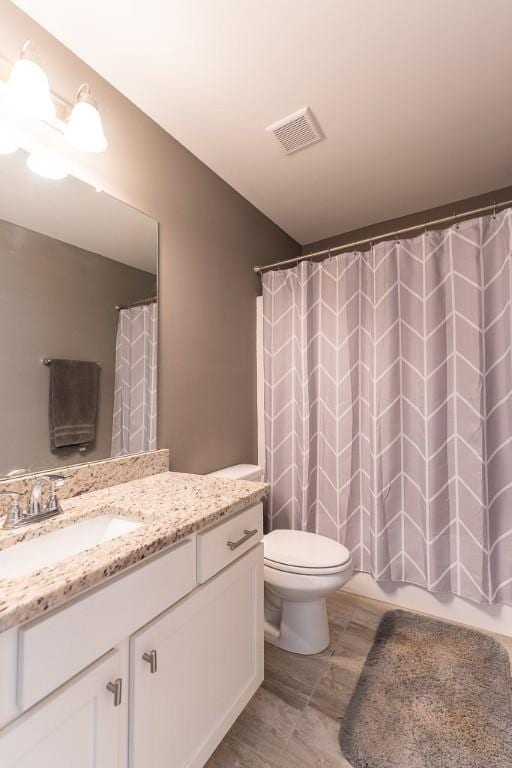 bathroom with toilet, visible vents, a shower with shower curtain, and vanity