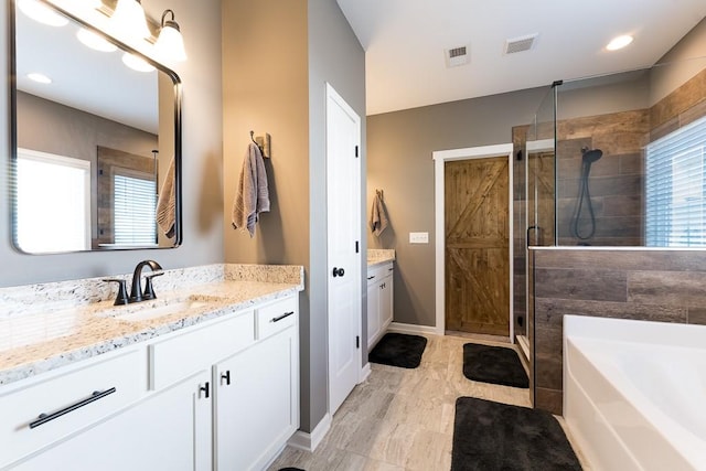 bathroom featuring visible vents, plenty of natural light, a shower stall, and vanity