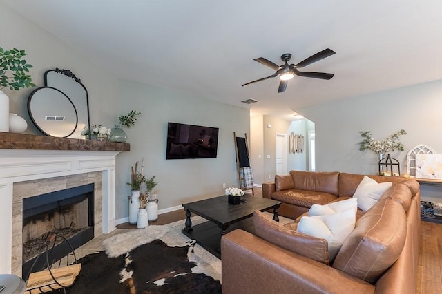 living area featuring ceiling fan, a fireplace, visible vents, and baseboards