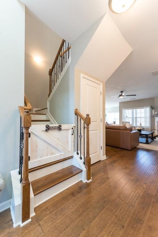 stairs featuring a ceiling fan, visible vents, baseboards, and hardwood / wood-style flooring