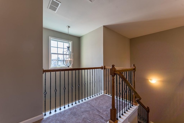 stairs with a chandelier, carpet, visible vents, and baseboards