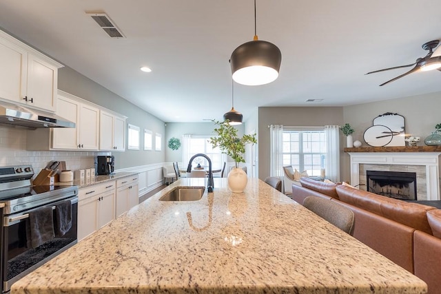 kitchen with visible vents, open floor plan, a sink, stainless steel range with electric stovetop, and under cabinet range hood