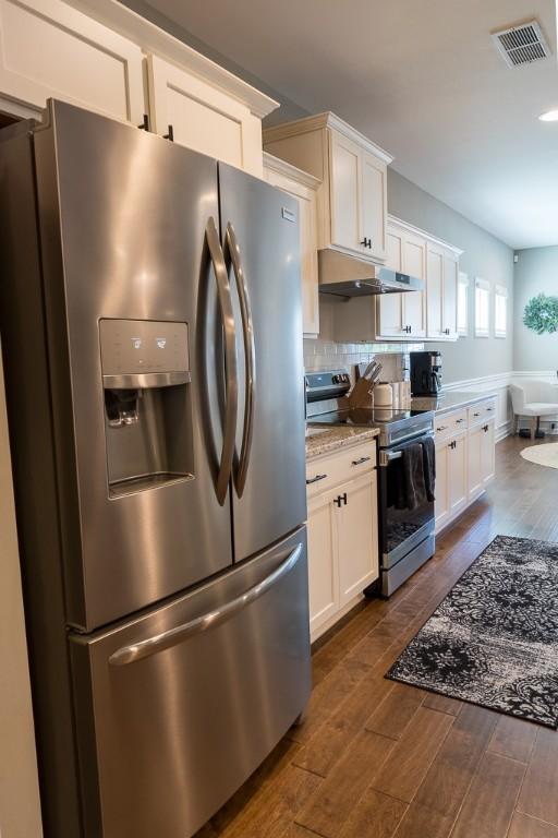 kitchen with appliances with stainless steel finishes, visible vents, under cabinet range hood, and dark wood-type flooring