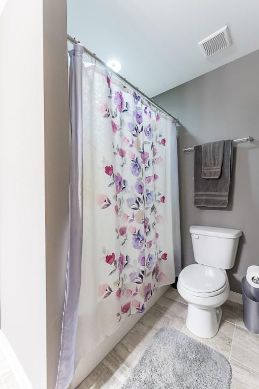 bathroom featuring shower / tub combo, baseboards, visible vents, and toilet