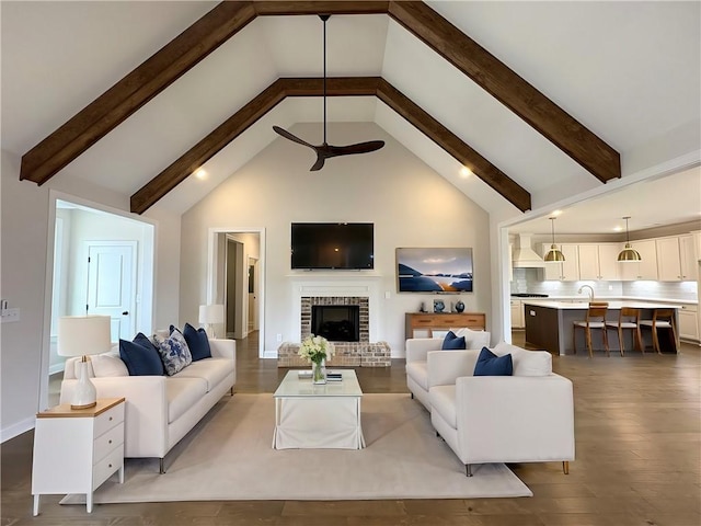 living room with high vaulted ceiling, a brick fireplace, beam ceiling, and wood finished floors