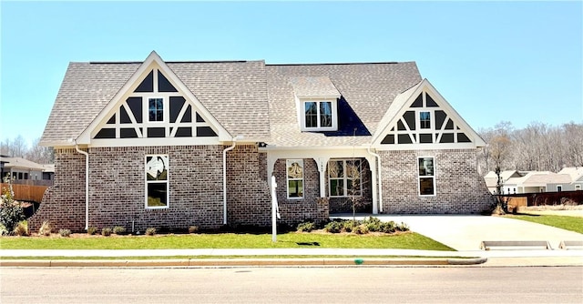 english style home featuring brick siding and a shingled roof