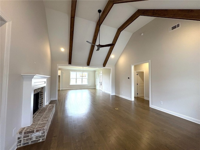 unfurnished living room featuring dark wood-style floors, a fireplace, visible vents, beamed ceiling, and baseboards