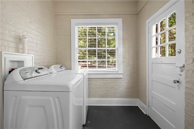 laundry room with washer and clothes dryer and brick wall