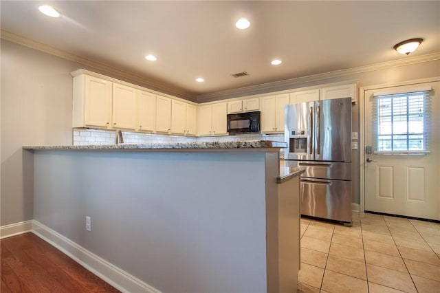 735 Hunter Ct, Auburn, AL 36832 - kitchen with stainless steel fridge with ice dispenser, black microwave, stone counters, decorative backsplash, and white cabinets