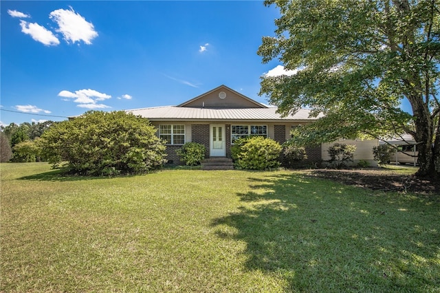 view of front of house featuring brick siding, metal roof, and a front yard