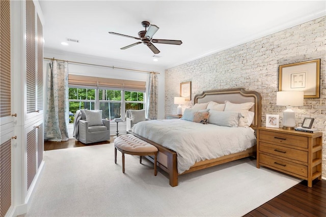 bedroom with ceiling fan, wood finished floors, and visible vents