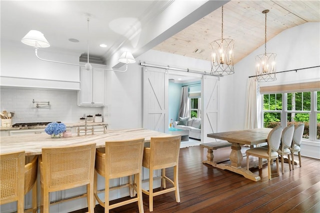 kitchen with a barn door, vaulted ceiling, decorative backsplash, and dark wood-type flooring