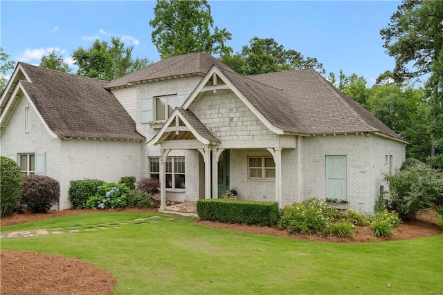 craftsman-style house featuring a front yard, brick siding, and roof with shingles