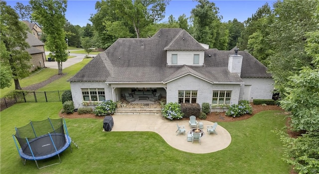 back of property featuring a trampoline, a yard, an outdoor fire pit, a patio area, and fence