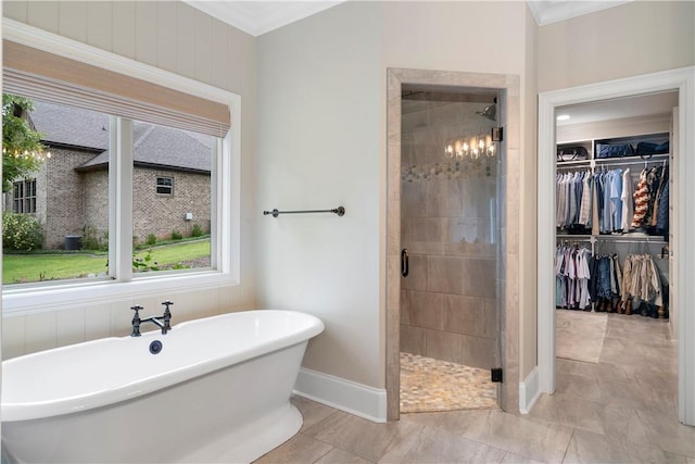 full bath featuring crown molding, a spacious closet, a shower stall, a freestanding tub, and baseboards