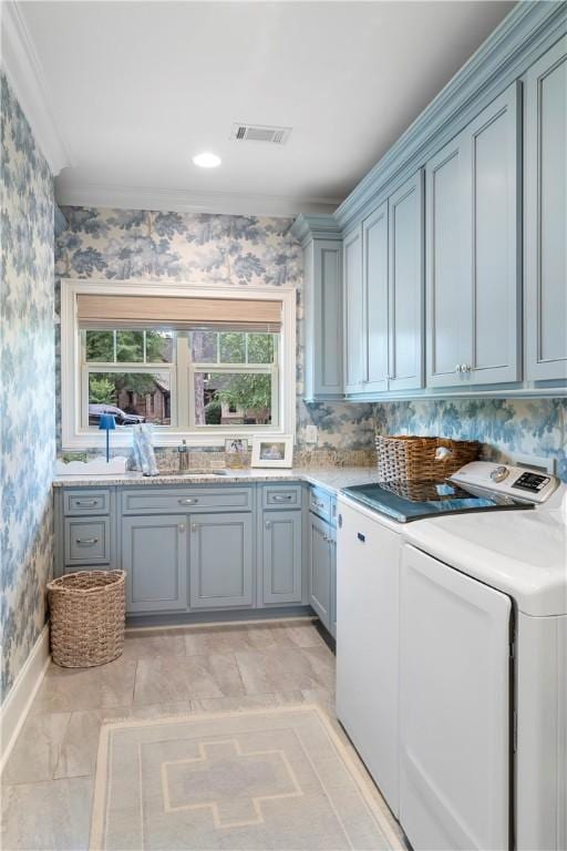 clothes washing area with cabinet space, visible vents, ornamental molding, separate washer and dryer, and wallpapered walls