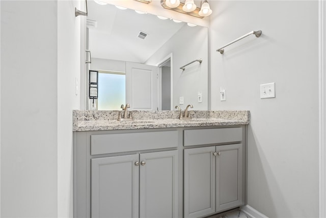 bathroom with lofted ceiling, visible vents, a sink, and double vanity