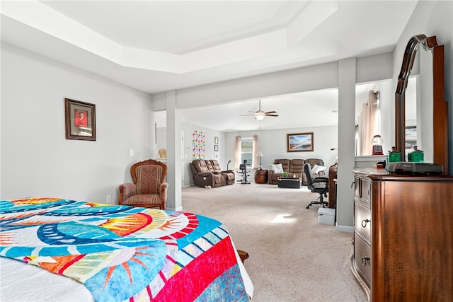 carpeted bedroom with a ceiling fan, a tray ceiling, and baseboards