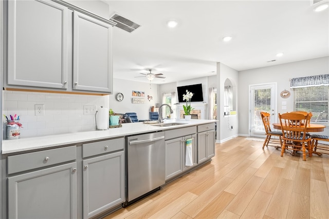 kitchen featuring gray cabinetry, a sink, light wood-style floors, backsplash, and dishwasher