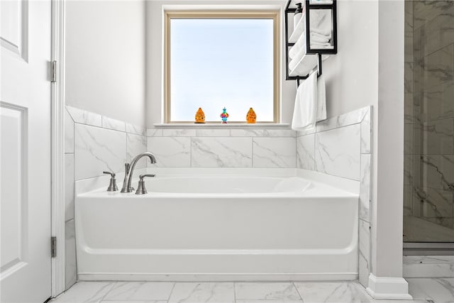 full bathroom featuring marble finish floor and a garden tub