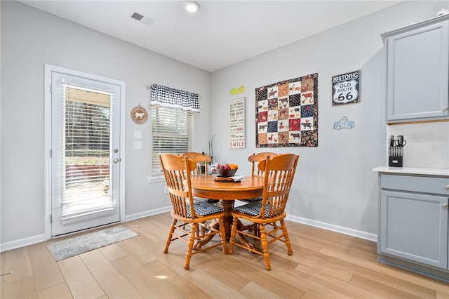 dining room featuring light wood-style floors, baseboards, and visible vents