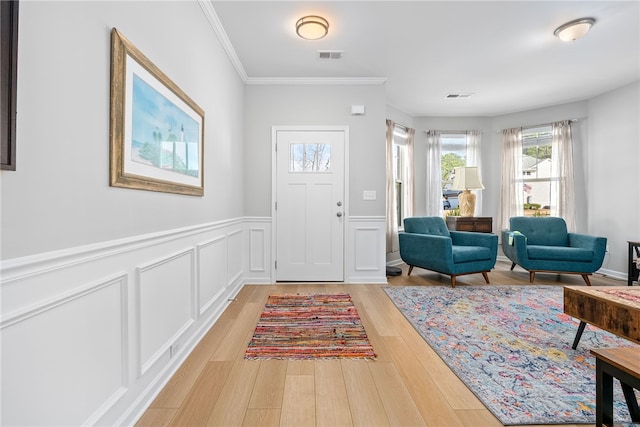 entryway with a decorative wall, wood finished floors, visible vents, and crown molding