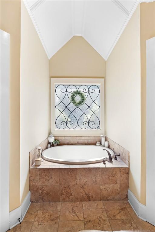 bathroom featuring vaulted ceiling and tiled bath