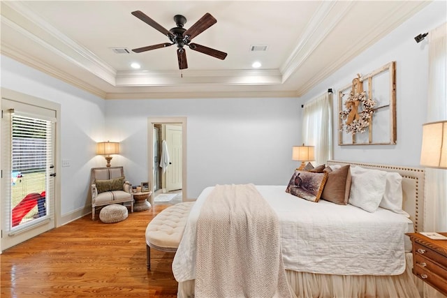 bedroom with crown molding, ceiling fan, a tray ceiling, and hardwood / wood-style floors