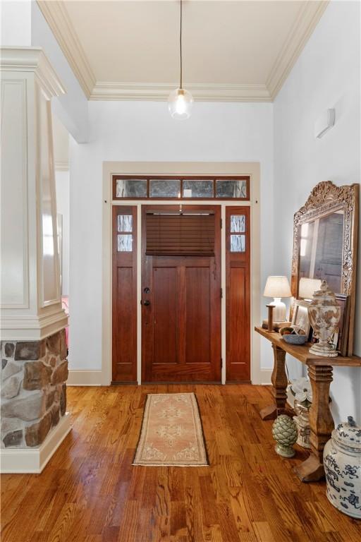 foyer entrance with hardwood / wood-style flooring and crown molding