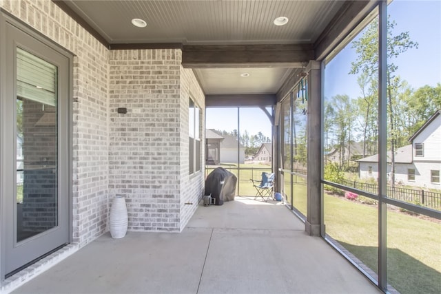 unfurnished sunroom featuring beam ceiling