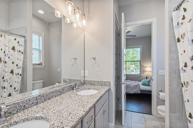 bathroom with a shower with shower curtain, vanity, toilet, and tile patterned floors