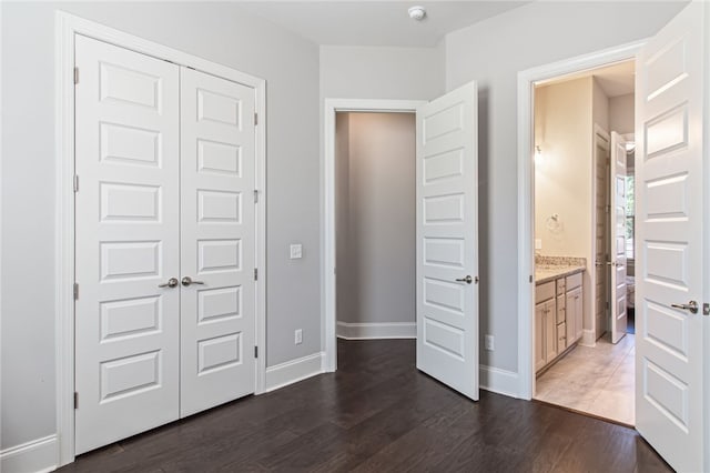 unfurnished bedroom featuring dark hardwood / wood-style flooring, ensuite bath, and a closet