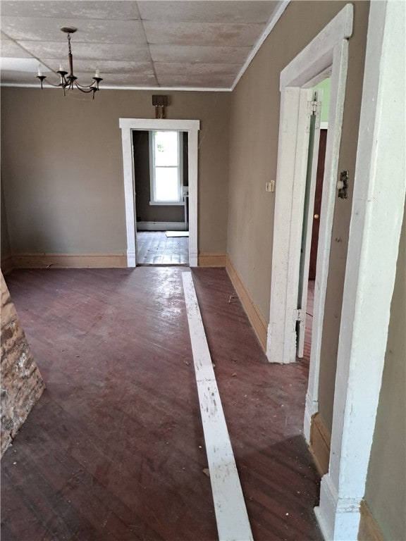 interior space featuring baseboards, a chandelier, and hardwood / wood-style floors