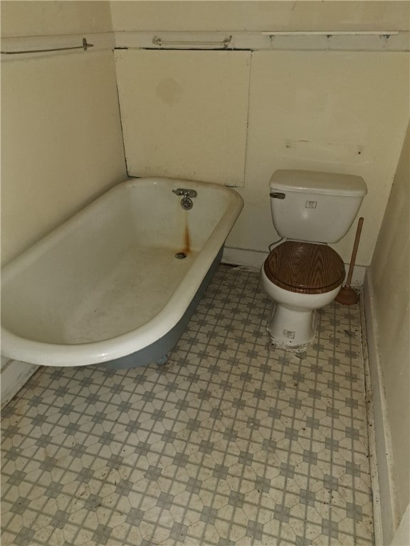 bathroom featuring toilet, a tub to relax in, and tile patterned floors