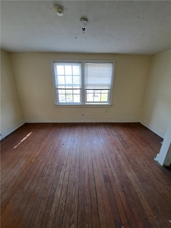 unfurnished room featuring dark wood-type flooring and baseboards