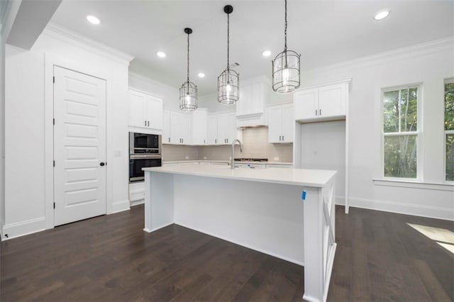 kitchen with pendant lighting, white cabinets, and an island with sink