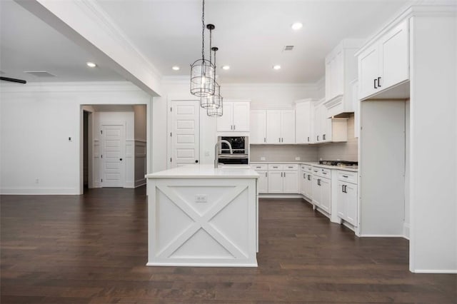 kitchen with decorative light fixtures, dark wood-type flooring, white cabinetry, and a center island with sink