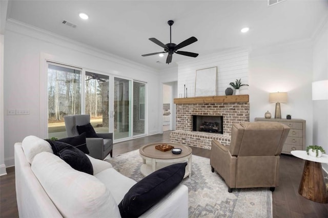 living room featuring ceiling fan, dark hardwood / wood-style floors, a brick fireplace, and ornamental molding