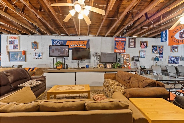 living area with ceiling fan and concrete block wall