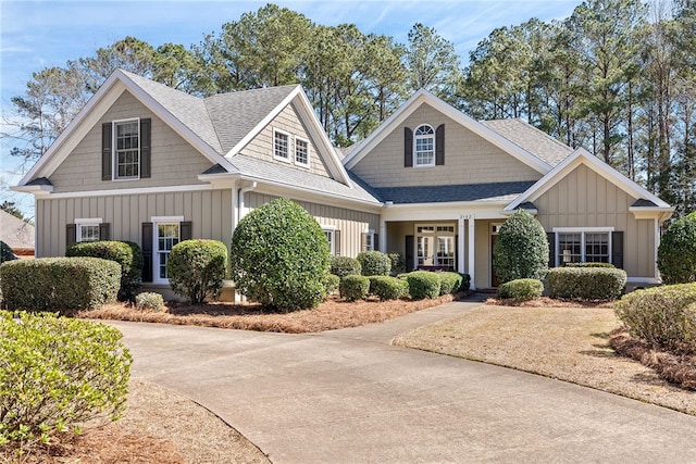 craftsman house with driveway, a shingled roof, and board and batten siding