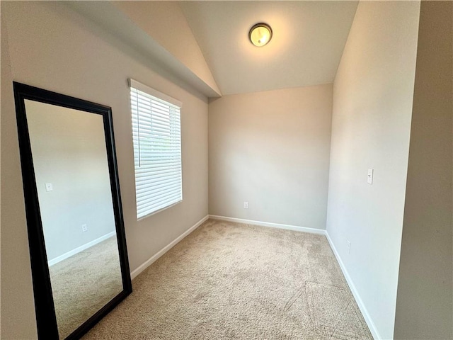 empty room with baseboards, lofted ceiling, and carpet