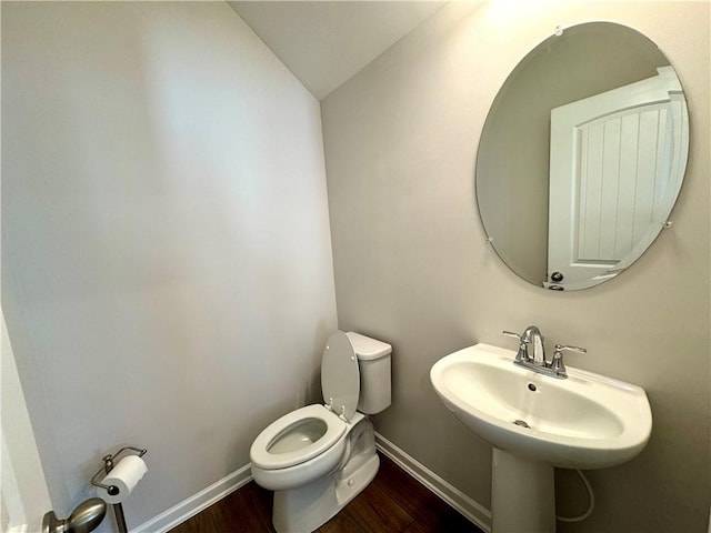 bathroom featuring lofted ceiling, a sink, baseboards, toilet, and wood finished floors