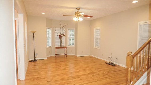 unfurnished room with ceiling fan, a textured ceiling, and light wood-type flooring